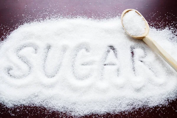 Inscription sugar made into pile of white granulated sugar — Stock Photo, Image