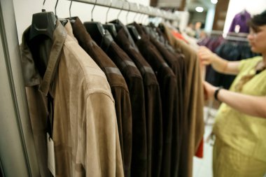 Doğal kürk mantolar bir mağazadaki askılara ağırlık verir. Sarı kazaklı kız mağazadan kürk manto seçiyor.