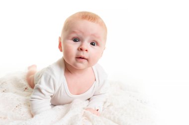 Beyaz tenli sevimli bir bebek. 4 aylık küçük bir bebek yumuşak bir battaniyenin üzerinde uzanıyor ve kameraya bakıyor.