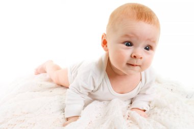 Beyaz tenli sevimli bir bebek. 4 aylık küçük bir bebek yumuşak bir battaniyenin üzerinde uzanıyor ve kameraya bakıyor.