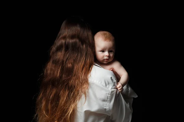 年轻的黑发妈妈 白衬衫 抱着一个刚出生的儿子 一个4个月大的婴儿在她怀里在黑色背景上 — 图库照片