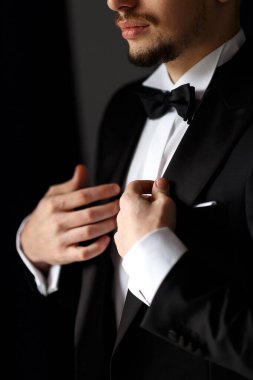 Şık bir düğün sabahı takım elbiseli bir damat. Bir adam beyaz gömlek ve siyah takım elbise giyiyor.