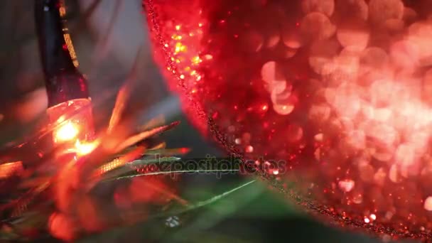 Christmas and New Year Decoration. Fairy Lights Close Up Near Red Shiny Bauble on Christmas Tree. — Stock Video