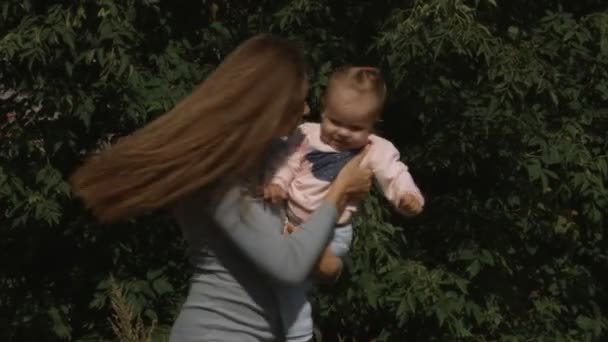 母亲和女婴在绿叶背景下旋转的缓慢动作 长头发的妇女 — 图库视频影像