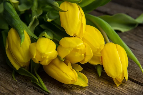 Tulipas amarelas na mesa de madeira velha rústica — Fotografia de Stock