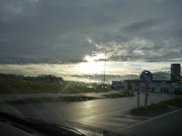 Estrada através de chuva vidro molhado com gotas de água — Fotografia de Stock