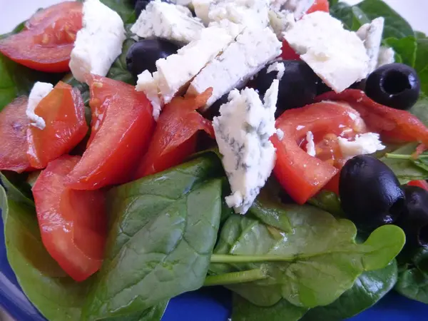 Portion od spinach salad with tomatoes and cheese — Stock Photo, Image