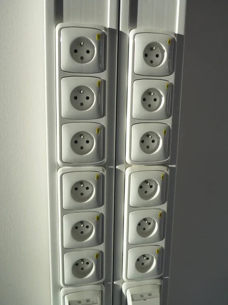 Många vita sockets på en vägg — Stockfoto