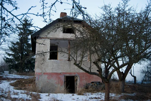 Старый заброшенный дом в саду зимой — стоковое фото