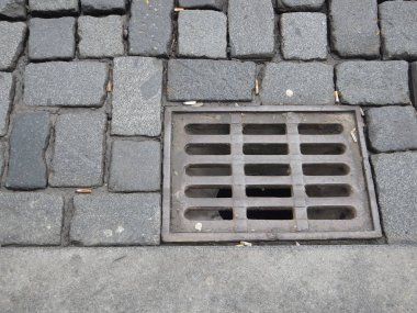 arnavut kaldırımlı bir sokakta ızgara ile su drenaj deliği