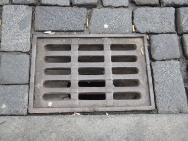 arnavut kaldırımlı bir sokakta ızgara ile su drenaj deliği