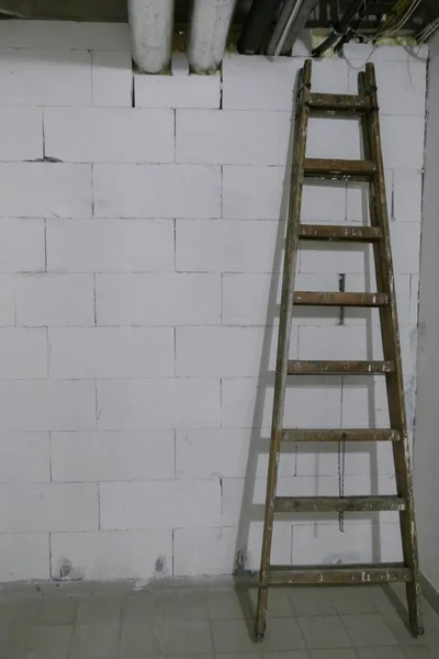Scala a pioli ad un muro di mattoni bianchi — Foto Stock