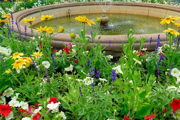 Wasserfontäne im Park mit Blumen — Stockfoto