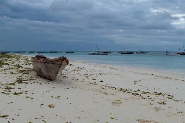 Романтический закат с лодкой на берегу океана — стоковое фото