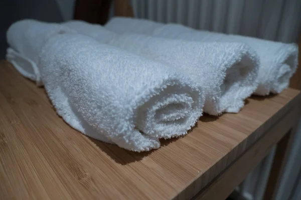 Walcowane białe ręczniki na drewnianym stole — Zdjęcie stockowe
