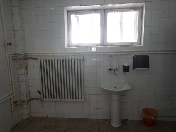 Старая грязная ванная комната с белой плиткой — стоковое фото