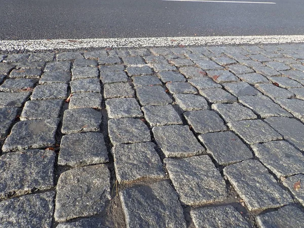 Kullersten asfalt konsistens våt efter regn — Stockfoto