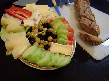 Akşam yemeğinde beyaz tabakta servis edilen çeşitli sebze ve peynir salataları.