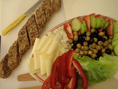 Akşam yemeğinde beyaz tabakta servis edilen çeşitli sebze ve peynir salataları.