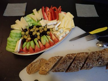 Akşam yemeğinde beyaz tabakta servis edilen çeşitli sebze ve peynir salataları.