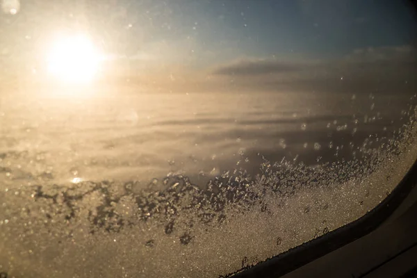 从天上结冰的飞机窗口往外看 — 图库照片