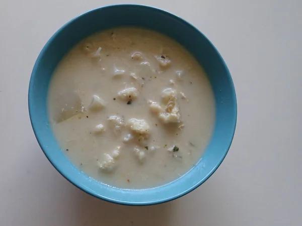 portion of a white cauliflower milk soup served in a bowl