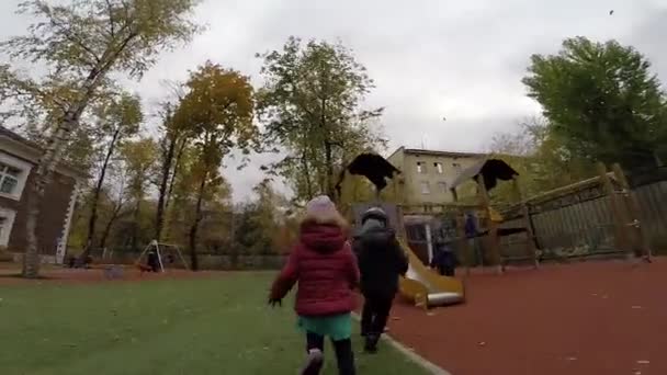 女の子は秋に遊び場に沿って実行されます — ストック動画