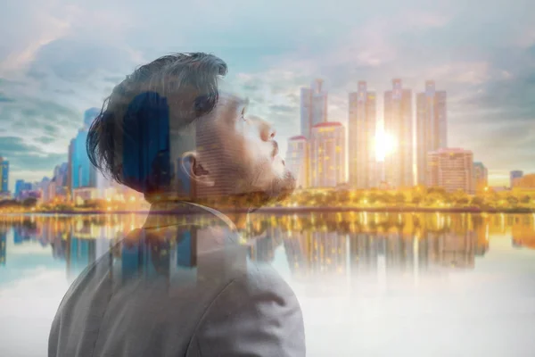 Double exposure of businessman and blurred city in sunrise.