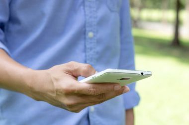 Doğa arka plan üzerinde akıllı telefon kullanan bir adam