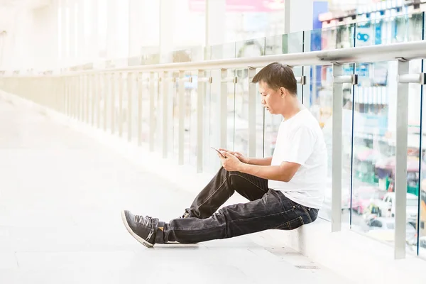 Un hombre sentado en una acera Navegar por Internet y en el teléfono inteligente —  Fotos de Stock