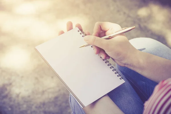 Una mujer escribiendo algo en un cuaderno vacío . — Foto de Stock