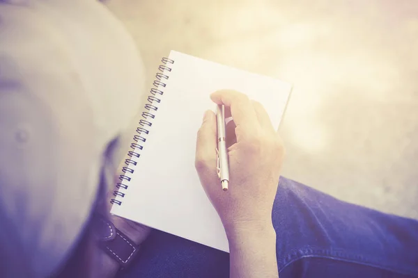Una mujer escribiendo algo en un cuaderno vacío . — Foto de Stock