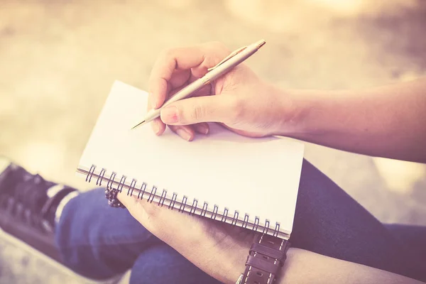 Una mujer escribiendo algo en un cuaderno vacío . — Foto de Stock