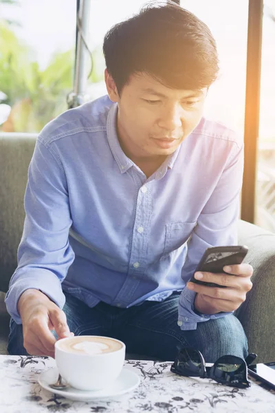 Un hombre está utilizando el teléfono inteligente en coffeeshop . —  Fotos de Stock