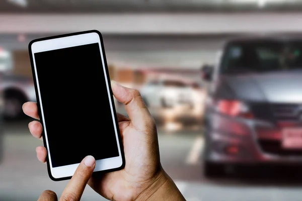 Hand hold smartphone in blurred parking lot inside the building. — Stock Photo, Image