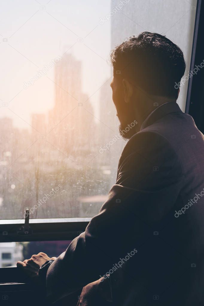 Stressed business man standing by the window.