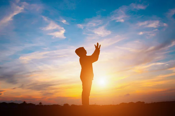 Het silhouet van een persoon in het gebed bij zonsondergang. — Stockfoto