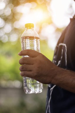 Asya adam el bokeh içecek su şişesi tutarak wi arka plan