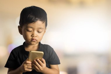 Asyalı çocuk 2 yaşında smartphone arka plan bulanık. Seçici odak