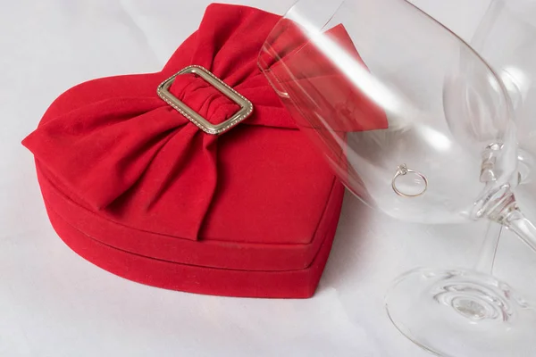 Copa de vino y caja en forma de corazón con anillos de boda en la mesa — Foto de Stock