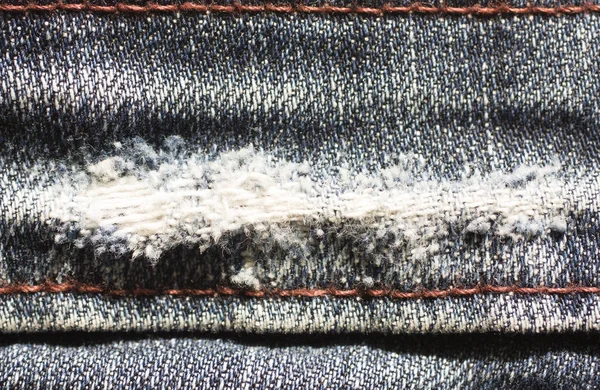 Rippade trasiga blå jeans tyg sömmar med orange tråd. — Stockfoto