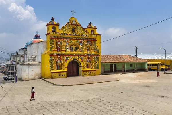 La colorida iglesia de San Andrés Xecul y tres mujeres mayas locales caminando por la calle en Guatemala —  Fotos de Stock