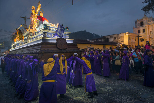 Penitents carrying a float with the image of Jesus Christ in an Easter procession at night during the Holy Week in Antigua, Guatemala