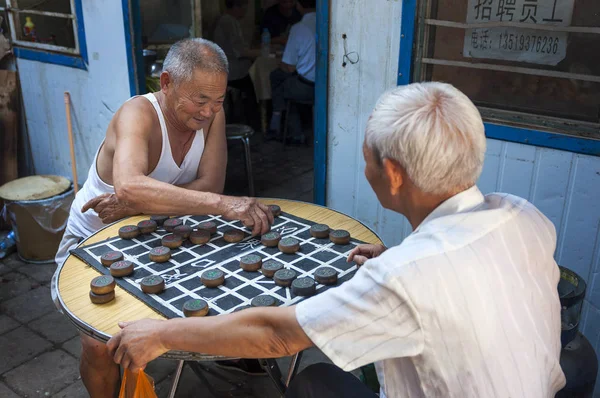 Dos hombres chinos jugando Ajedrez Chino (Xiangqi) en una calle de la ciudad de Dunhuang, China — Foto de Stock