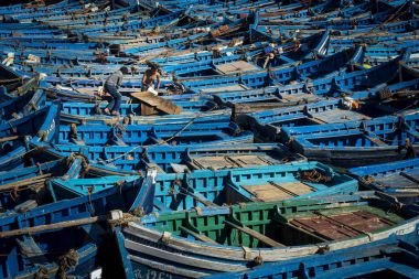 Two fisherman working in the traditional blue fishing boats docked in the fishing harbour of Essouria in the Atlantic Coast of Morocco. clipart