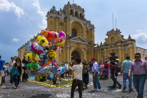 Niño vendiendo globos en una calle de la ciudad vieja de Antigua con el Hospital San Pedro al fondo, en Guatemala —  Fotos de Stock