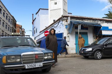 People in a street with cars and shops in the town of Chefchaouen in Morocco, North Africa clipart