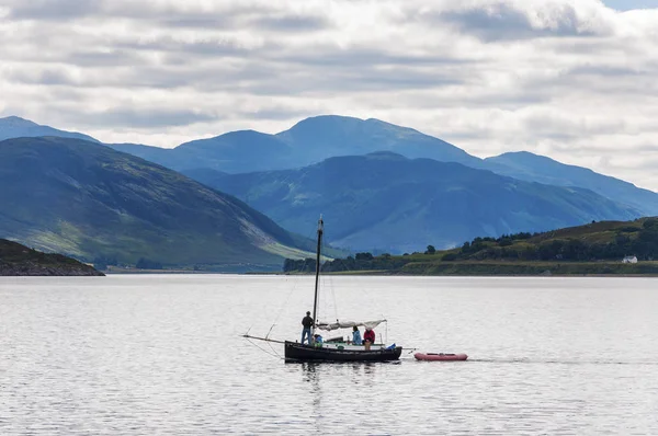 Άνθρωποι σε ένα μικρό ιστιοπλοϊκό σκάφος μπροστά από το μικρό χωριό του Ούλαπουλ στα Highlands της Σκωτίας, Ηνωμένο Βασίλειο — Φωτογραφία Αρχείου