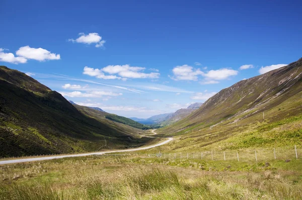 Route de campagne sinueuse le long d'une vallée dans les Highlands écossais, Royaume-Uni — Photo