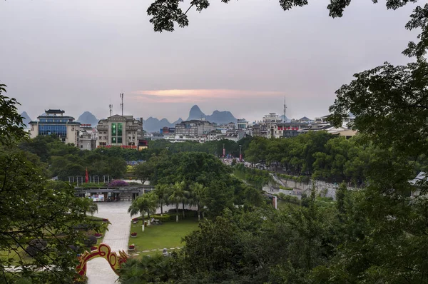 Uitzicht op de skyline van de stad van Guilin waar de beroemde kalkstenen pieken op de achtergrond bij zonsondergang, in China — Stockfoto